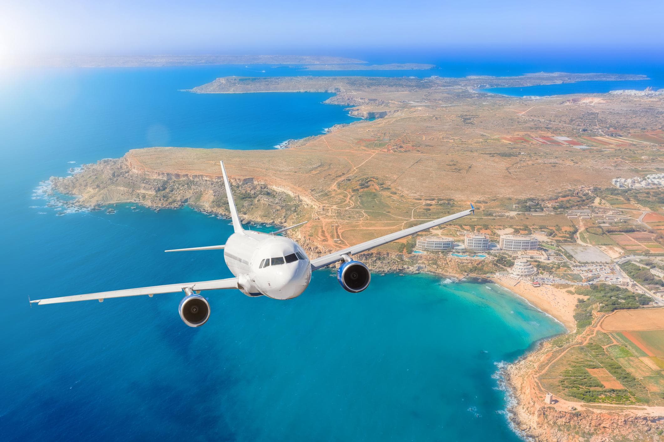 Airplane flying over a Mediterranean coastline
